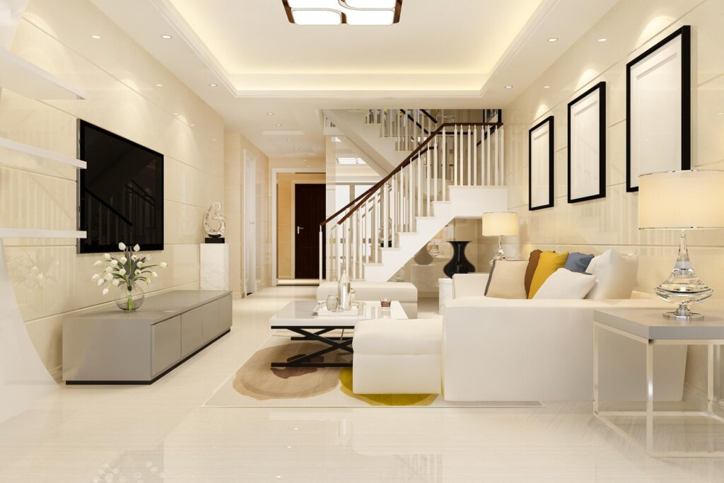 Bright, modern living room featuring a white sofa, coffee table, TV unit, and staircase, with decorative vases and artwork on the walls.